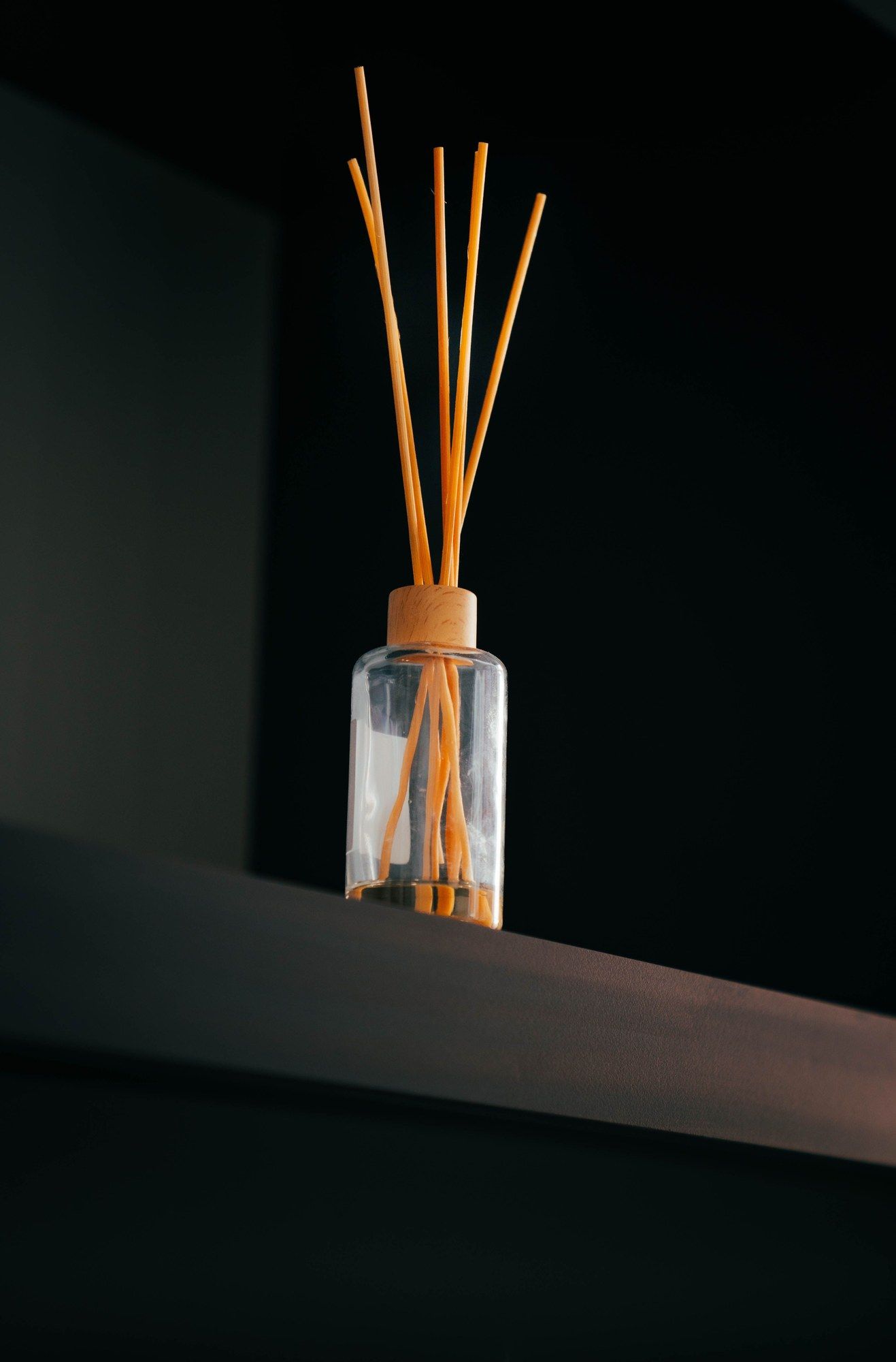 Difusor de varillas minimalista sobre un estante oscuro