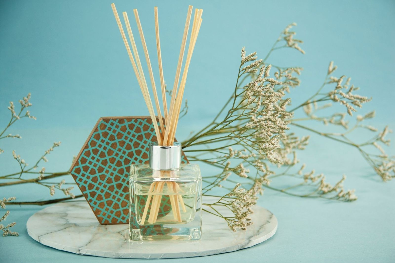 Varillas de aroma en frasco de vidrio junto a una rama de gypsophila sobre mármol