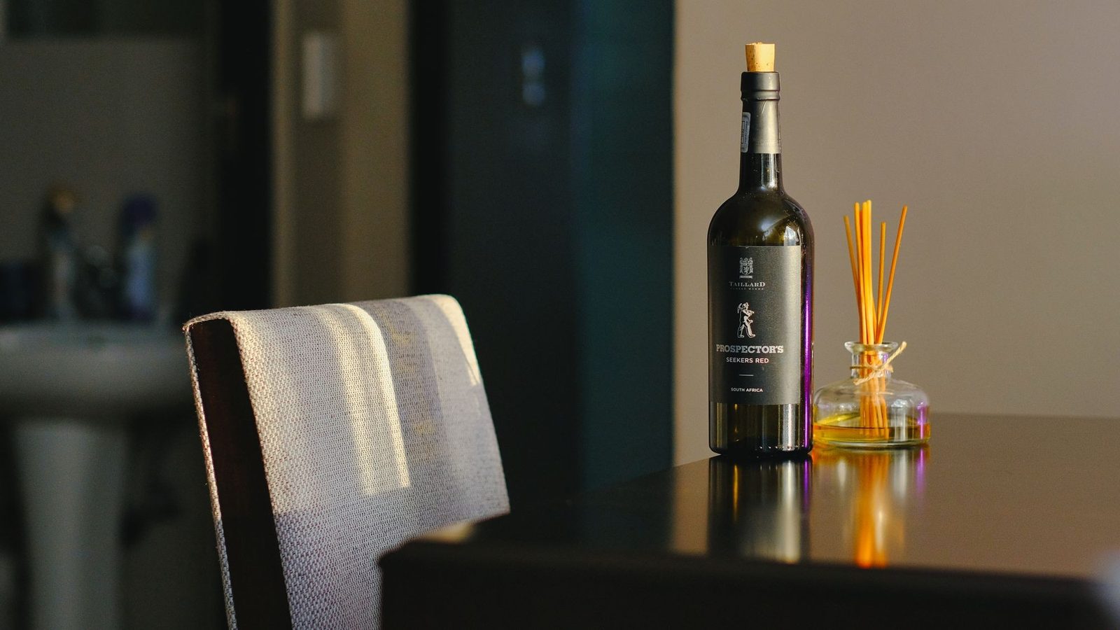 Difusor de varillas y una botella sobre una mesa en un interior cálido